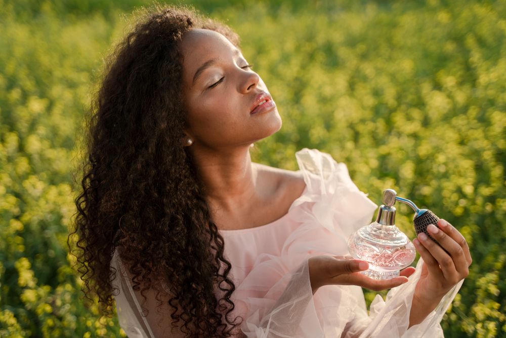 Mulher segurando frasco de perfume ao ar livre