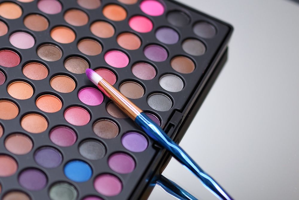 Pincéis de maquiagem ao lado de paleta colorida