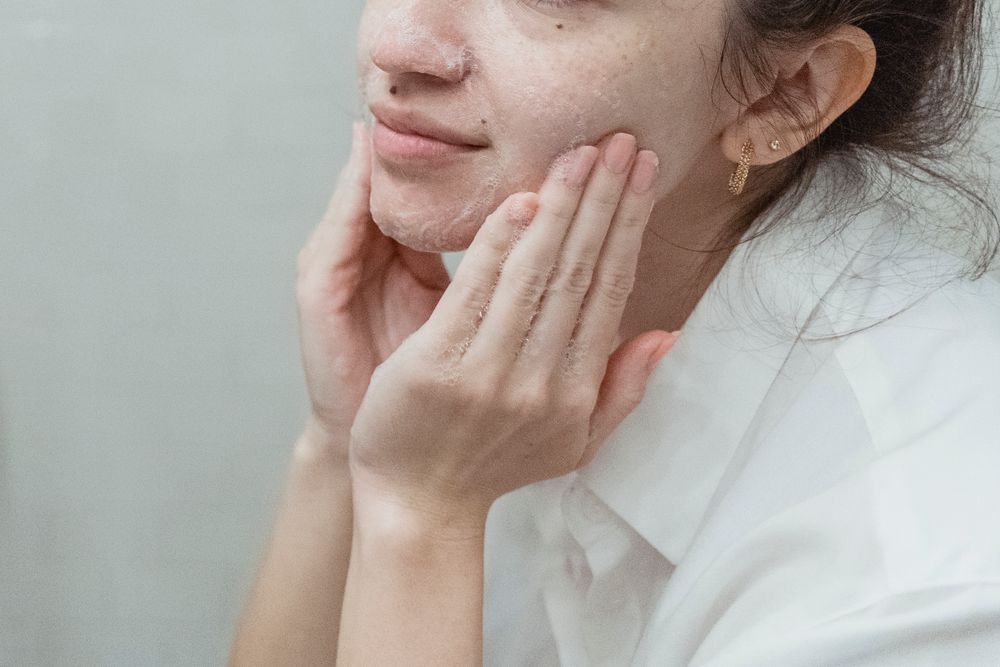Mulher lavando o rosto com sabonete facial na pia